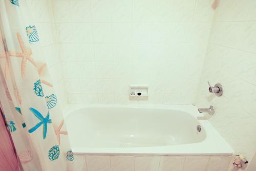 La salle de bains est pourvue d'une baignoire blanche et d'un rideau de douche. dans l'établissement Wish Inn Chidlom By GO INN - วิช อินน์ ชิดลม, à Makkasan