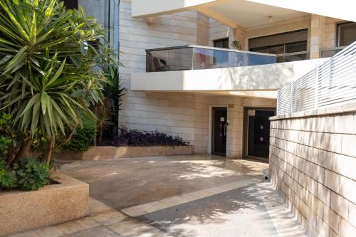 a building with a palm tree in front of it at Garden House By IsrApart in Ra‘ananna