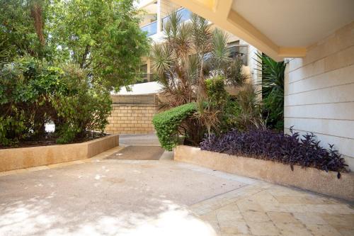 a building with trees and plants in a courtyard at Garden House By IsrApart in Ra‘ananna