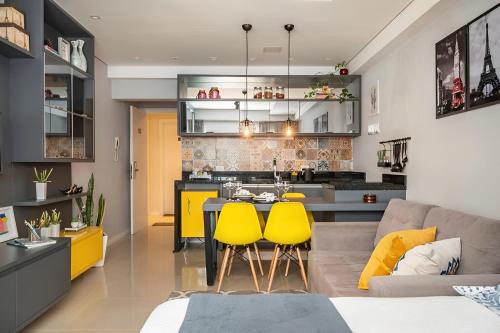 a kitchen and living room with yellow chairs and a table at Acolhedor Studio no Batel/Água Verde em frente ao Shopping Curitiba in Curitiba