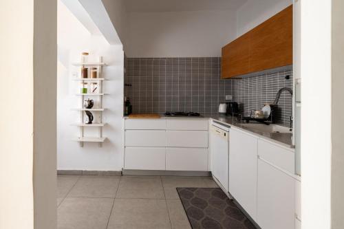 een keuken met witte kasten en een wastafel bij Family Apartment By IsrApart in Ramat Gan