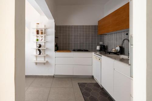a kitchen with white cabinets and a sink at Family Apartment By IsrApart in Ramat Gan