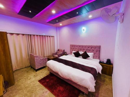 Hotel candlewood Shimla في شيملا: غرفة نوم بسرير كبير واضاءة ارجوانية