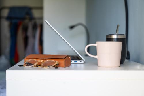a pair of glasses and a cup on a counter with a laptop at Family Apartment By IsrApart in Ramat Gan