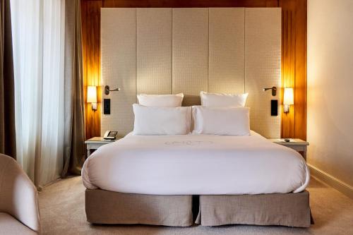 - une chambre avec un grand lit et des oreillers blancs dans l'établissement Relais & Châteaux La Maison Des Têtes, à Colmar