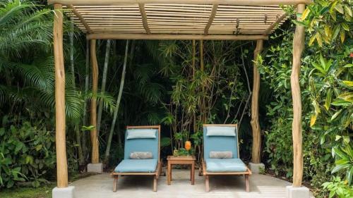 two chairs and a table under a pergola at Cala Luna Boutique Hotel & Villas in Tamarindo