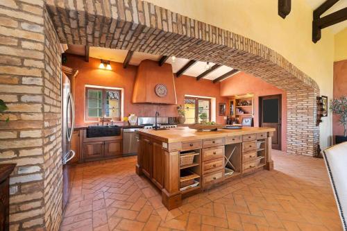 a large kitchen with a brick wall and an archway at Tuscan Villa w/Vineyard Views! in Murrieta