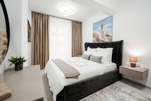 a white bedroom with a large white bed and a window at Pandora's Apartments in Suceava