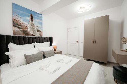 蘇恰瓦的住宿－Pandora's Apartments，卧室配有一张白色大床,墙上挂有绘画作品