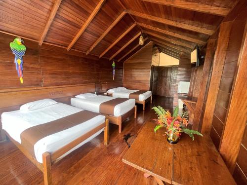 a room with three beds and a wooden ceiling at Wasai Puerto Maldonado Eco Lodge in Puerto Maldonado