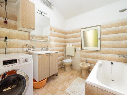 a bathroom with a washing machine and a sink at Rosemary Apartments in Duće