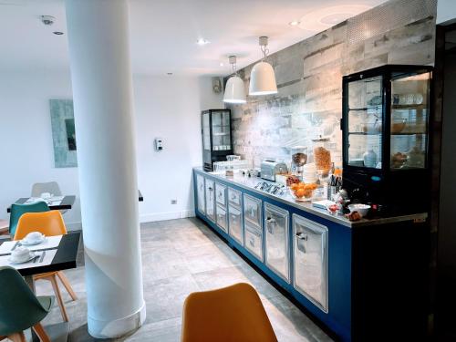 a kitchen with a counter with orange chairs at Brasilia Hôtel in Palavas-les-Flots