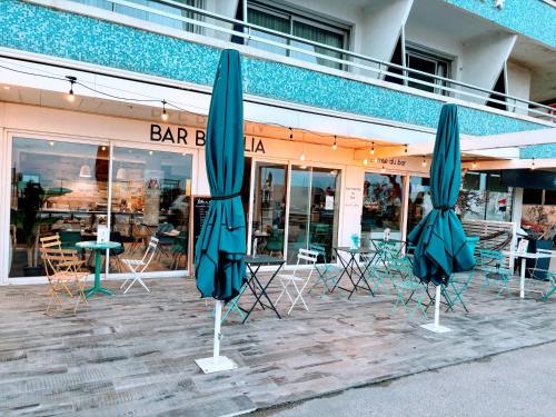 two closed umbrellas in front of a restaurant at Brasilia Hôtel in Palavas-les-Flots