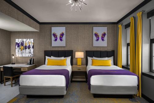 a hotel room with two beds and a desk and a desk at The Admiral, Downtown Historic District in Mobile