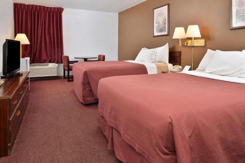 a hotel room with two beds and a flat screen tv at America's Best Value Inn Beardstown in Beardstown