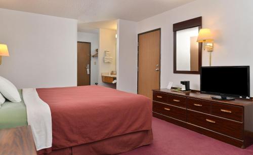 a hotel room with a bed and a flat screen tv at America's Best Value Inn Beardstown in Beardstown