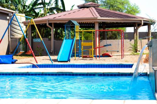 a swimming pool with a slide and a playground at Makobaneng Guesthouse in Ga-Raphokola