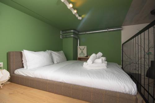 弗次瓦夫的住宿－Wrocław Airport Green Studio，一间卧室配有一张带白色床单和绿色墙壁的床。