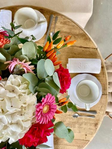 una mesa de madera con un plato con flores. en Les Terrasses de Bélarga - Maison d'hôtes - Piscine et Jacuzzi, en Bélarga