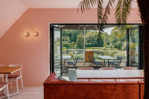 a room with tables and chairs and a large window at Modern en sfeervol appartement aan de Zoete Waters in Oud-Heverlee