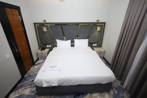 sypialnia z dużym łóżkiem z białą pościelą i poduszkami w obiekcie Khan Palace2 w mieście Türkistan