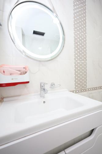 La salle de bains est pourvue d'un lavabo blanc et d'un miroir. dans l'établissement Khan Palace2, à Türkistan