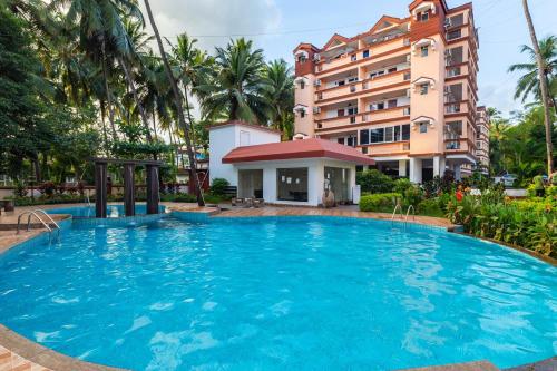 a large swimming pool in front of a building at Johnnie Holiday Homes in Arpora