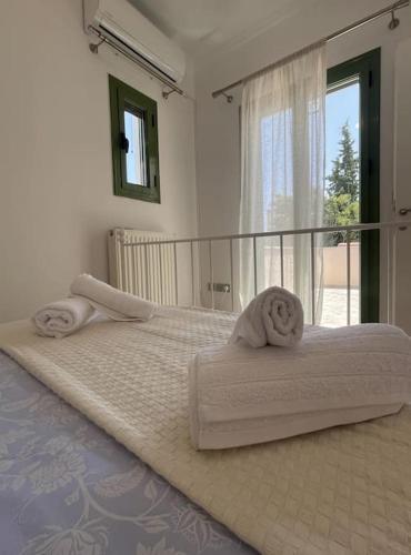 a bedroom with two white beds with a window at La nymphe Aegina in Áyioi Asómatoi