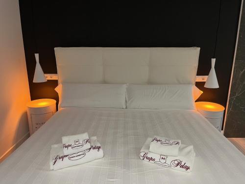 a white bed with two towels on top of it at H. Pelayo Autocheck-In Suites con Jacuzzi in Noja