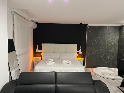 um quarto com uma cama com uma parede preta e um sofá em H. Pelayo Autocheck-In Suites con Jacuzzi em Noja