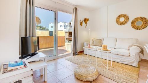 a living room with a white couch and a tv at Palm Beach House in Corralejo