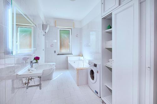 a white bathroom with a sink and a washing machine at Christa Guest House in Massa Lubrense