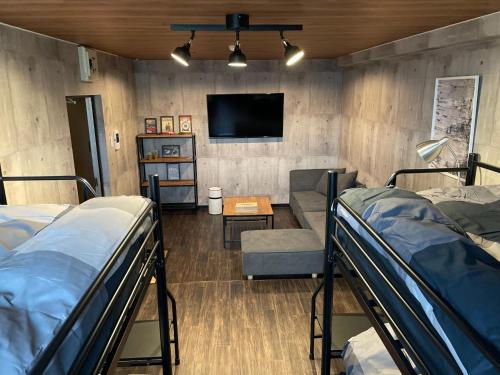 霧島市にあるInnCocoSumu？ - Vacation STAY 03969vの二段ベッド、テレビ、ソファが備わる客室です。
