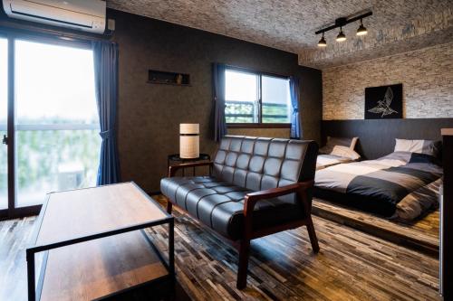 a living room with a leather couch and a bed at InnCocoSumu？ - Vacation STAY 09335v in Kirishima