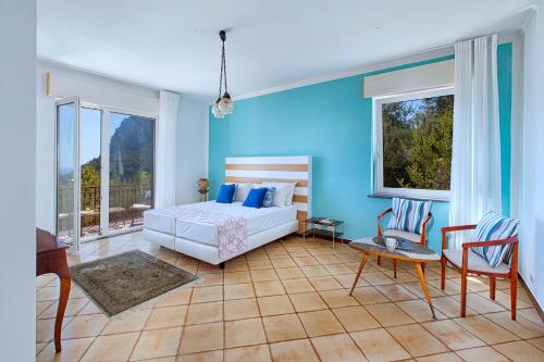 a bedroom with blue walls and a bed and chairs at Christa Guest House in Massa Lubrense