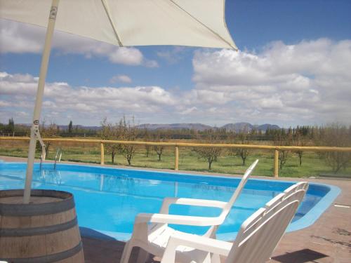 two chairs and an umbrella next to a swimming pool at Posada San Vicente in San Rafael