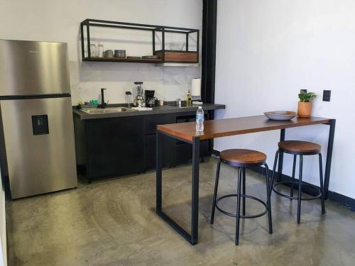 a kitchen with a table and two stools and a refrigerator at Loft plata en excelente ubicación in San Luis Potosí