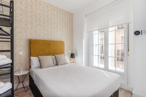 - une chambre avec un grand lit blanc et une fenêtre dans l'établissement BNBHolder Charming & Stylish CHUECA, à Madrid