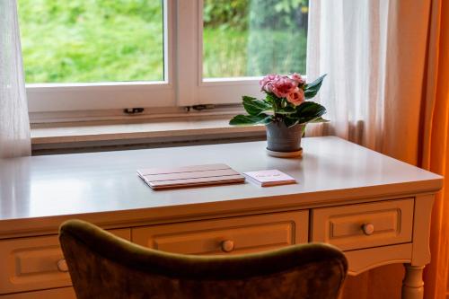 a table with a vase of flowers on it next to a window at Pension Landhaus- Frühstückspension im Brombachtal in Brombachtal