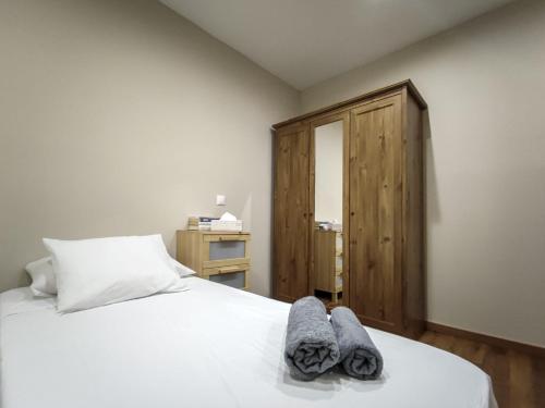 Un dormitorio con una cama blanca con toallas. en Pilar 19 - Piso céntrico en el Pilar, en Talavera de la Reina