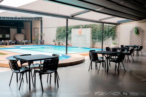 Megal Suites Hotel في سيوداد ديل إستي: مجموعة طاولات وكراسي بجانب مسبح