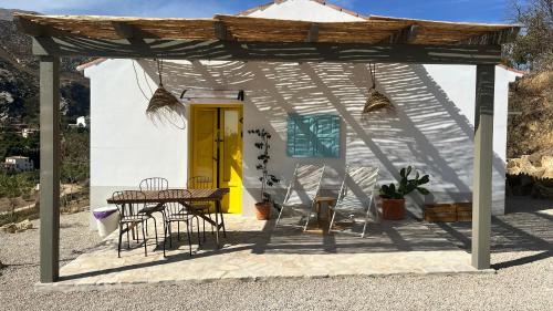 Casa blanca pequeña con mesa y sillas en Casita Malacitano, Caminito del Rey, en Valle de Abdalajís