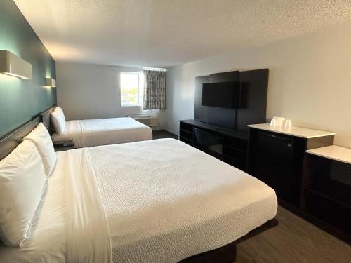 a hotel room with two beds and a flat screen tv at Studio 6 Suites Carson, CA in Carson