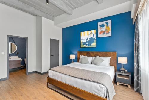 a bedroom with a large bed with a blue wall at Cannery Lofts Niagara in Niagara Falls