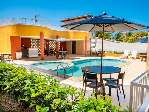 a patio with a table and umbrella next to a pool at Pousada Mares em Sergipe in Estância