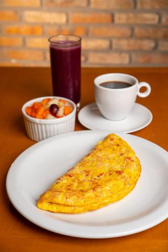 a white plate with a omelet and a cup of coffee at Roomo Transamerica Recife Boa Viagem in Recife