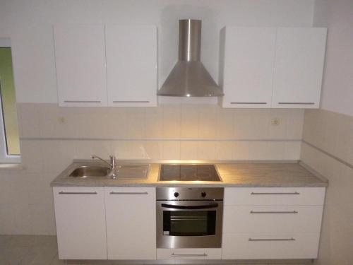 uma cozinha com armários brancos, um fogão e um lavatório em Apartment Mate em Korčula