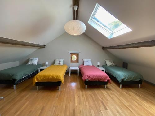a attic room with three beds and a window at Dordogne, Le Cambou, 5 ch avec piscine et terrain 3 ha in Vergt-de-Biron
