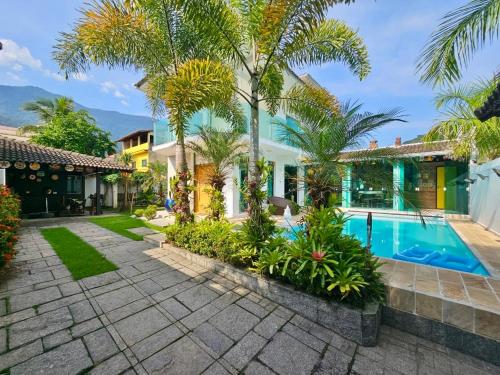 einen Außenblick auf ein Haus mit einem Pool und Palmen in der Unterkunft Casa de praia mangaratiba in Mangaratiba