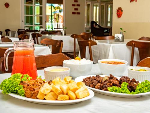 a table with two plates of food and drinks at Pousada Mares em Sergipe in Estância